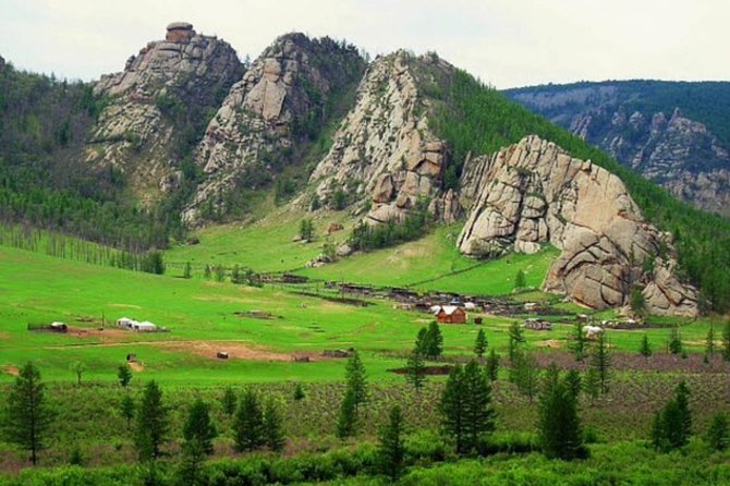 Granite outcrops above a green valley in Gorkhi-Terelj, with white gers on the grass